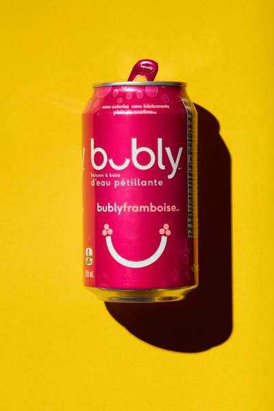 Pink can of Bubly sparkling water, raspberry flavor, set against a vibrant yellow background with a playful shadow.