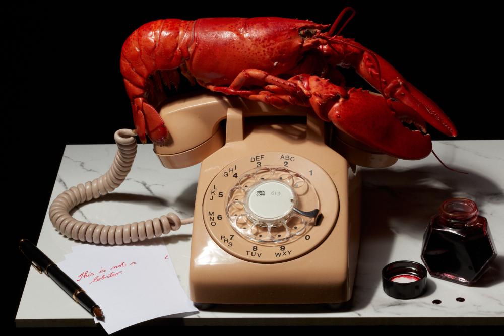 A surrealist scene inspired by Salvador Dali. A vibrant red lobster rests atop a vintage rotary phone. Scattered across the marble surface are ink-stained papers, a fountain pen, and a bottle of red ink. A handwritten note reads, 'This is not a lobster.'